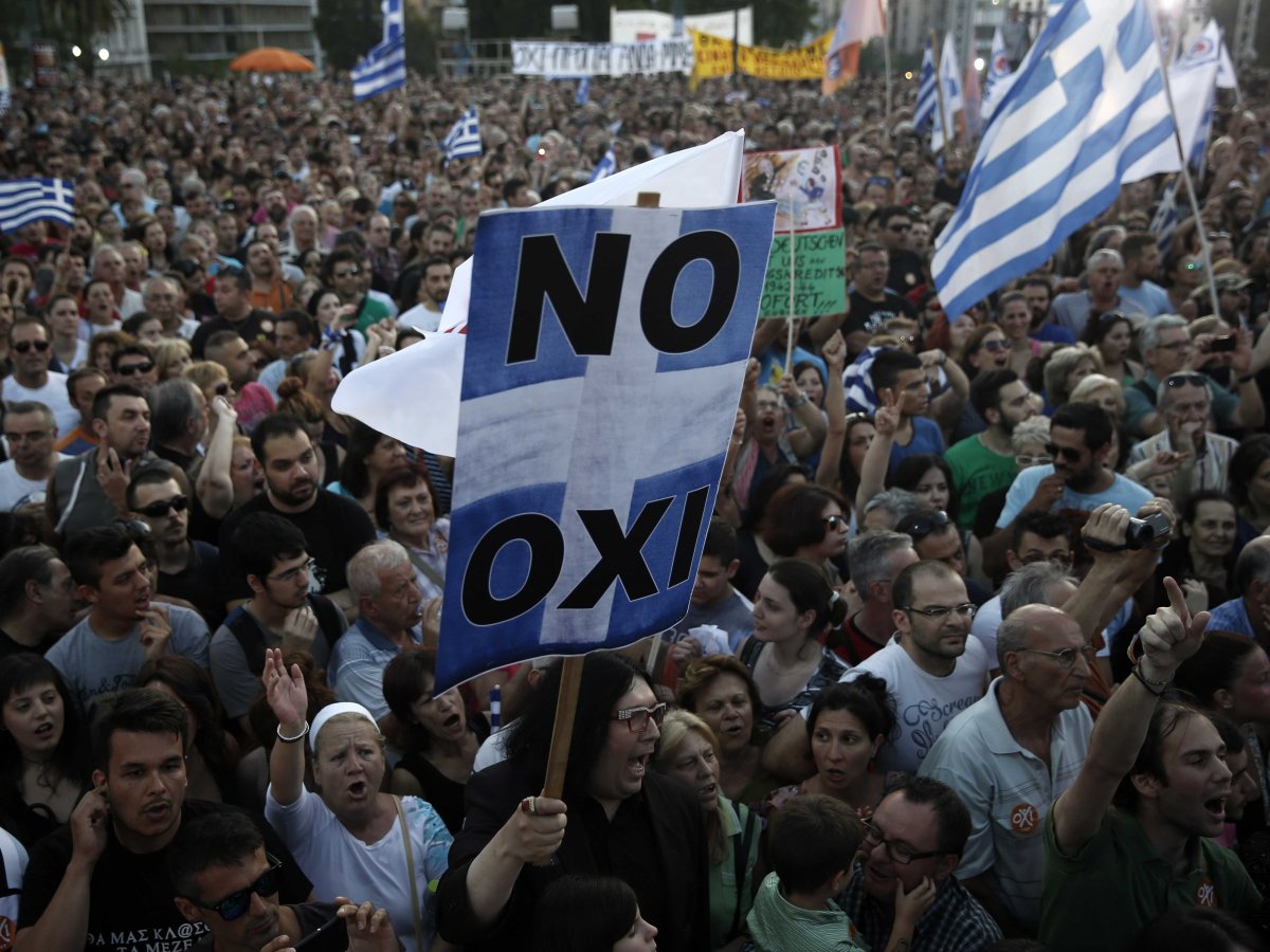 Un protestatar poartă un panou pe care scrie OXI („oxi” înseamnă „nu” în limba română).