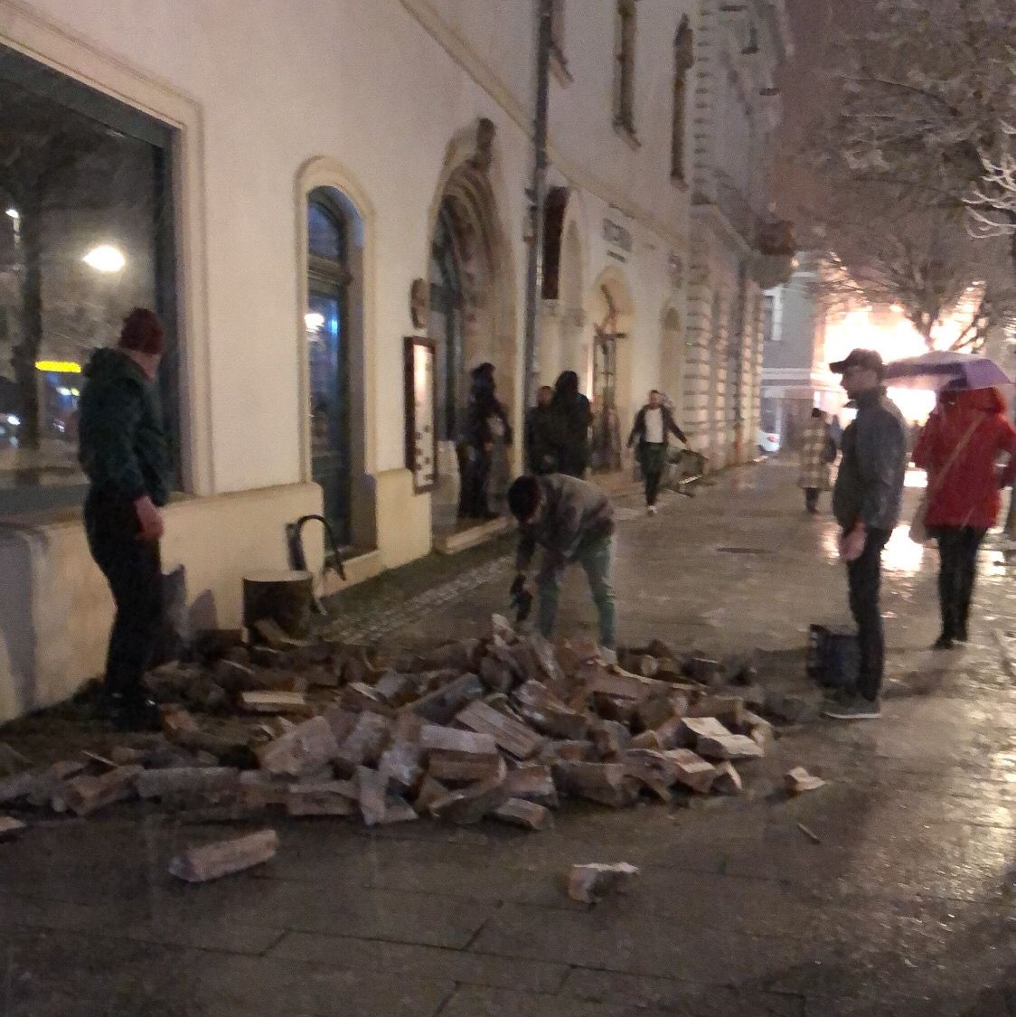 Mai mulți bărbați au ieșit în stradă să taie lemne, pe latura vestică a Pieței Unirii, vineri seară. FOTO: Monitorul de Cluj
