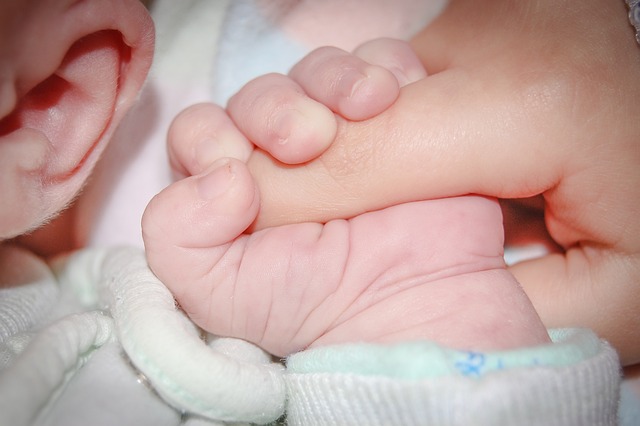 Bebeluș care ține în mână pe mama lui/ Foto: pixabay.com
