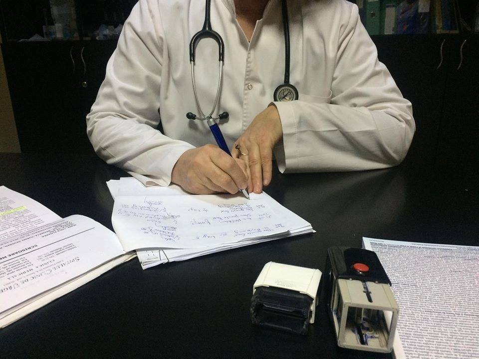 Medic care consultă și semnează documente. Foto: Facebook CNAS - Casa Naţională de Asigurări de Sănătate