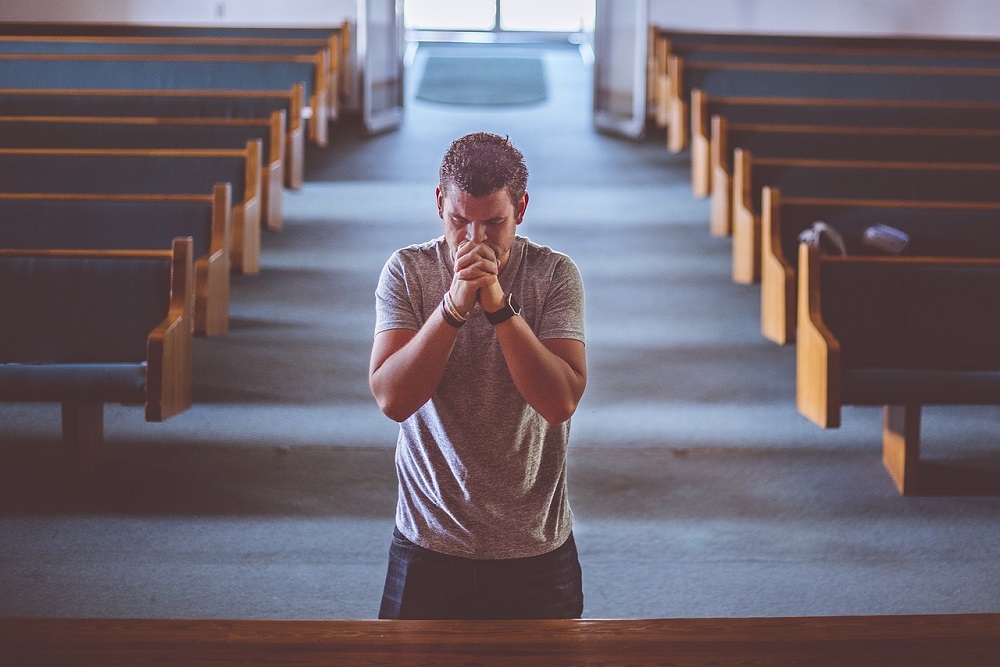 Bărbat care se roagă în biserică. Foto: Pixabay