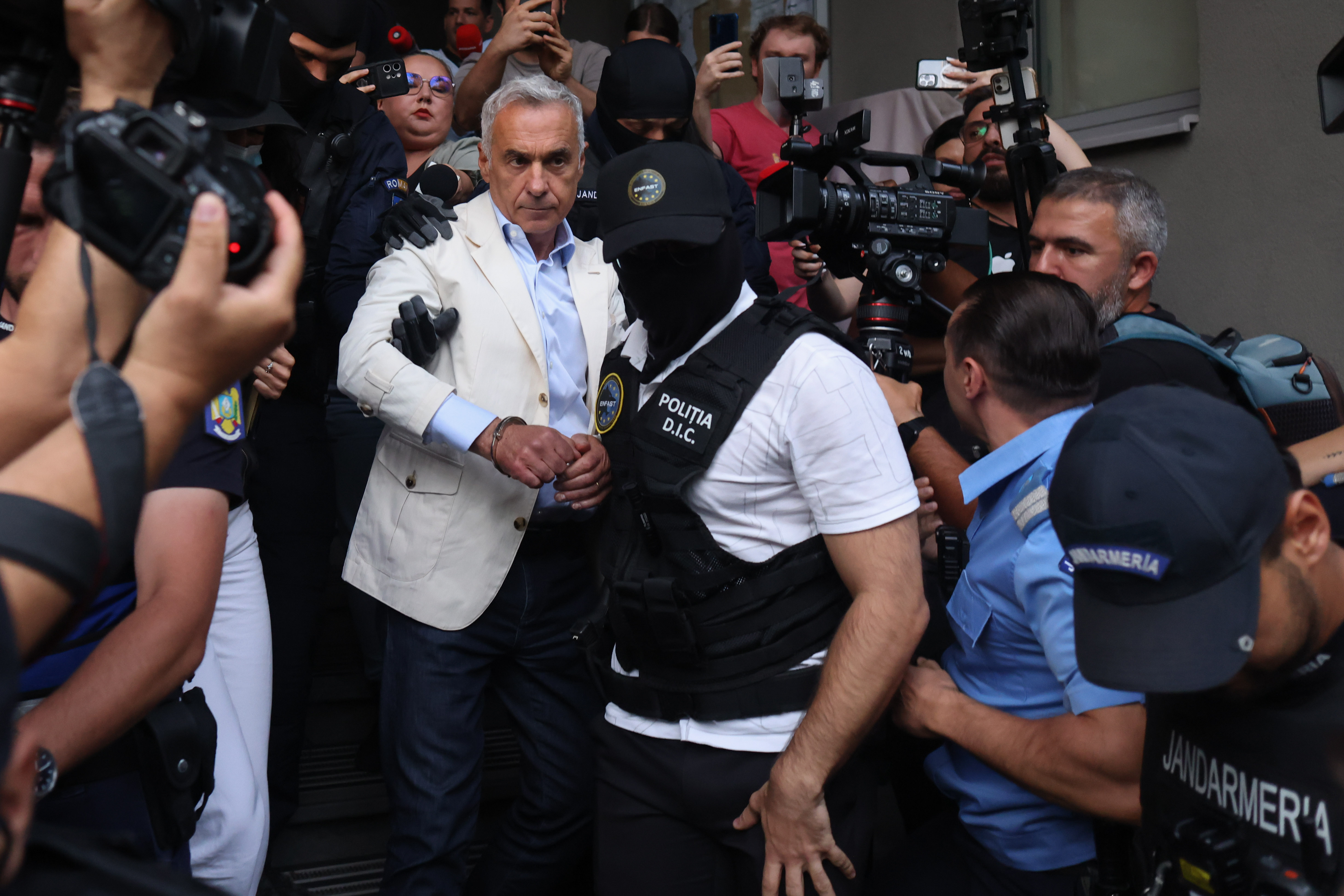 Călin Georgescu este escortat de către polițiști în afara sediului DIICOT după ce a fost reținut pentru 24 de ore, în București, 21 septembrie 2026. Inquam Photos / George Călin